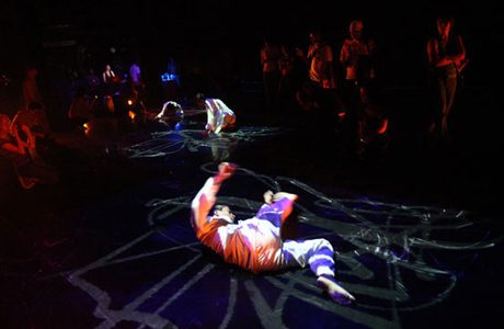 Dancers performing in a dark studio.