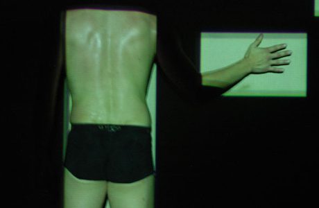 The back of a man is shown in a dark room.