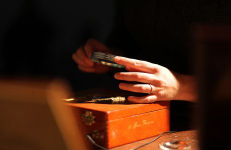 A woman is putting a watch into a wooden box.