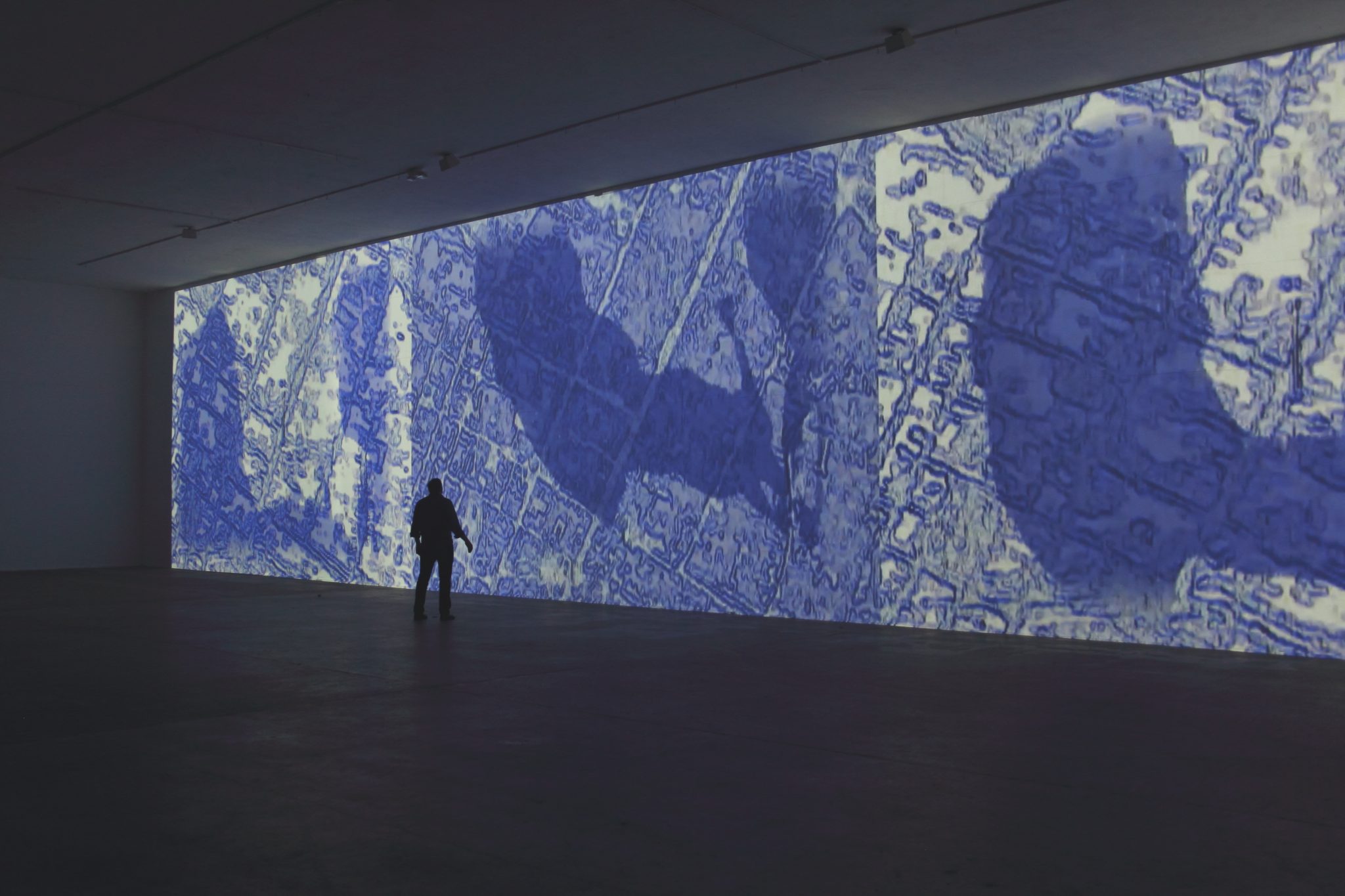 A person standing in front of a large blue wall.