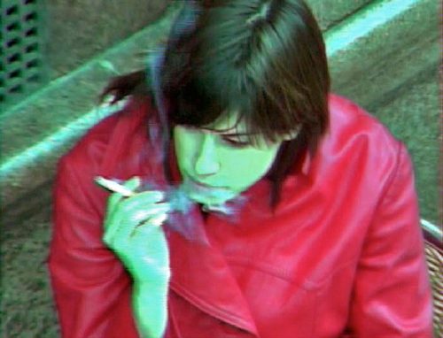 A woman in pink smoking a cigarette