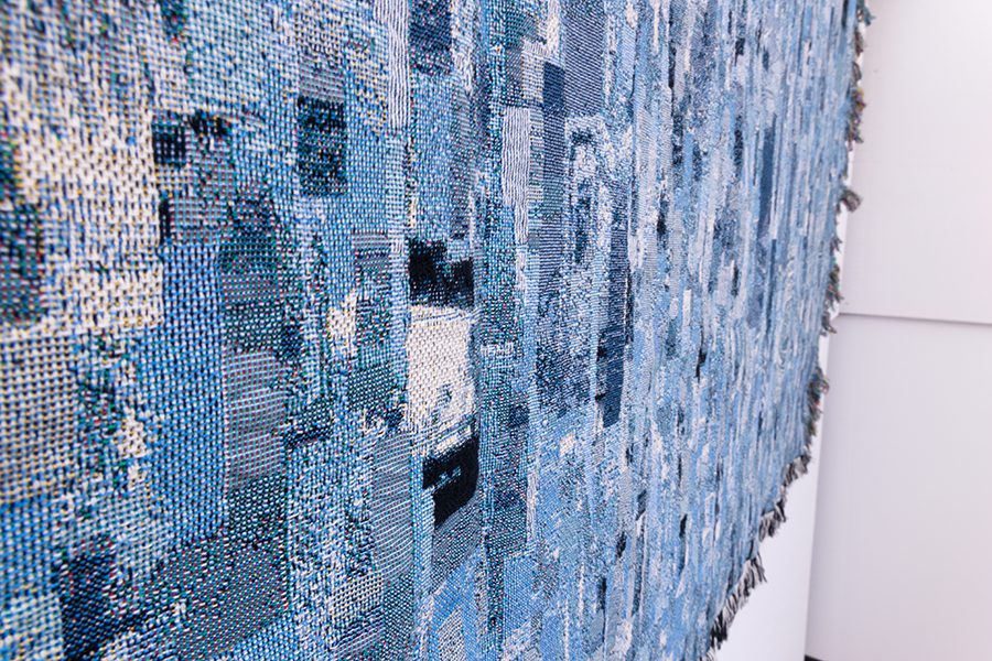 Blue digital woven tapestry hanging on wall